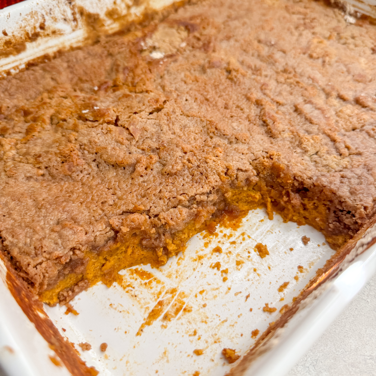 close up of the pumpkin dump cake in the pan with a piece or 2 missing