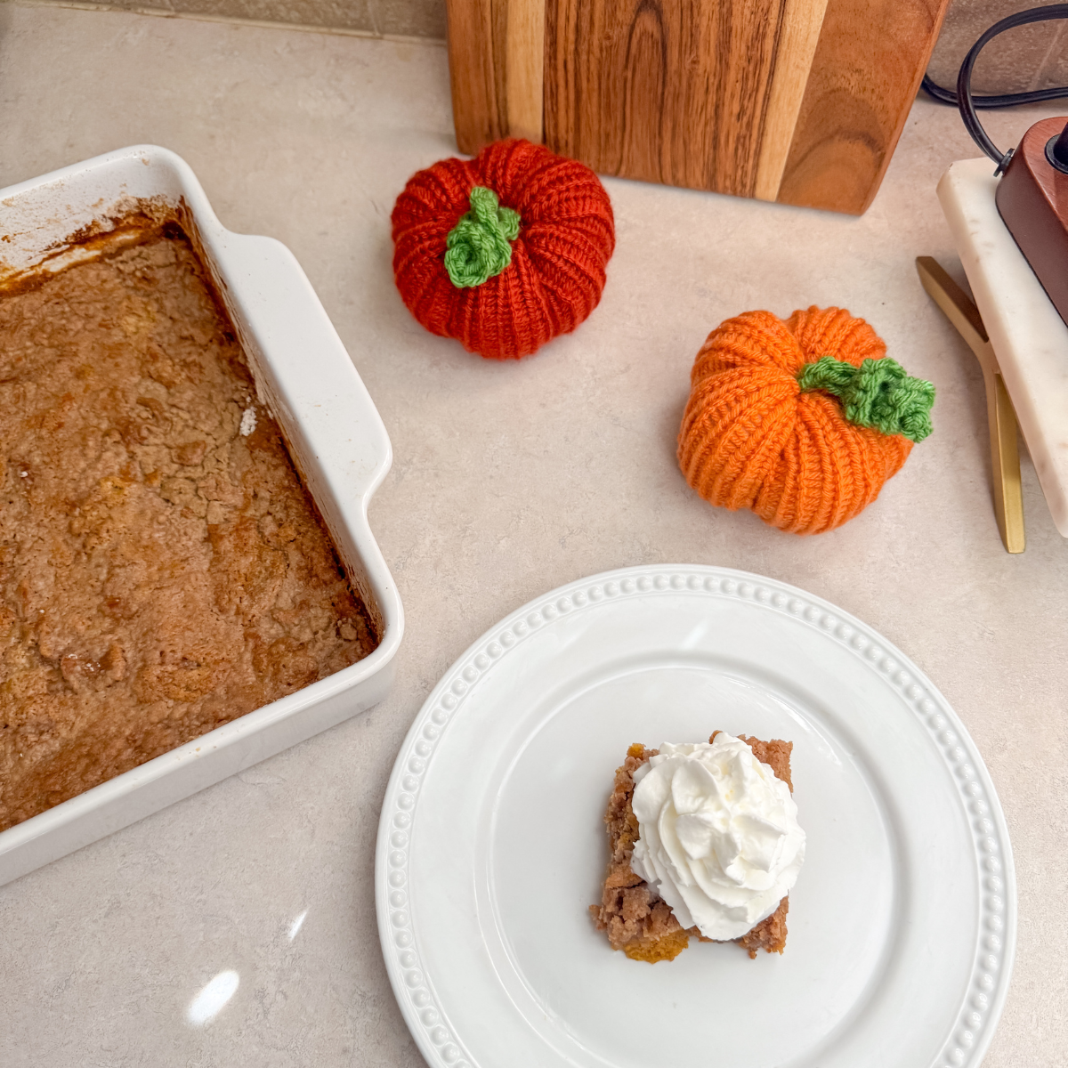 serving of pumpkin dump cake on a plate next to the pan